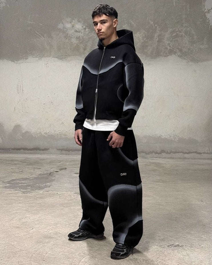 Person wearing a black hoodie and pants in an urban setting