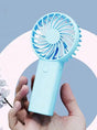 Hand holding a blue handheld fan with a light blue background